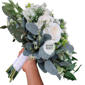Artificial ivory rose bouquet surrounded by lush greenery and leaves